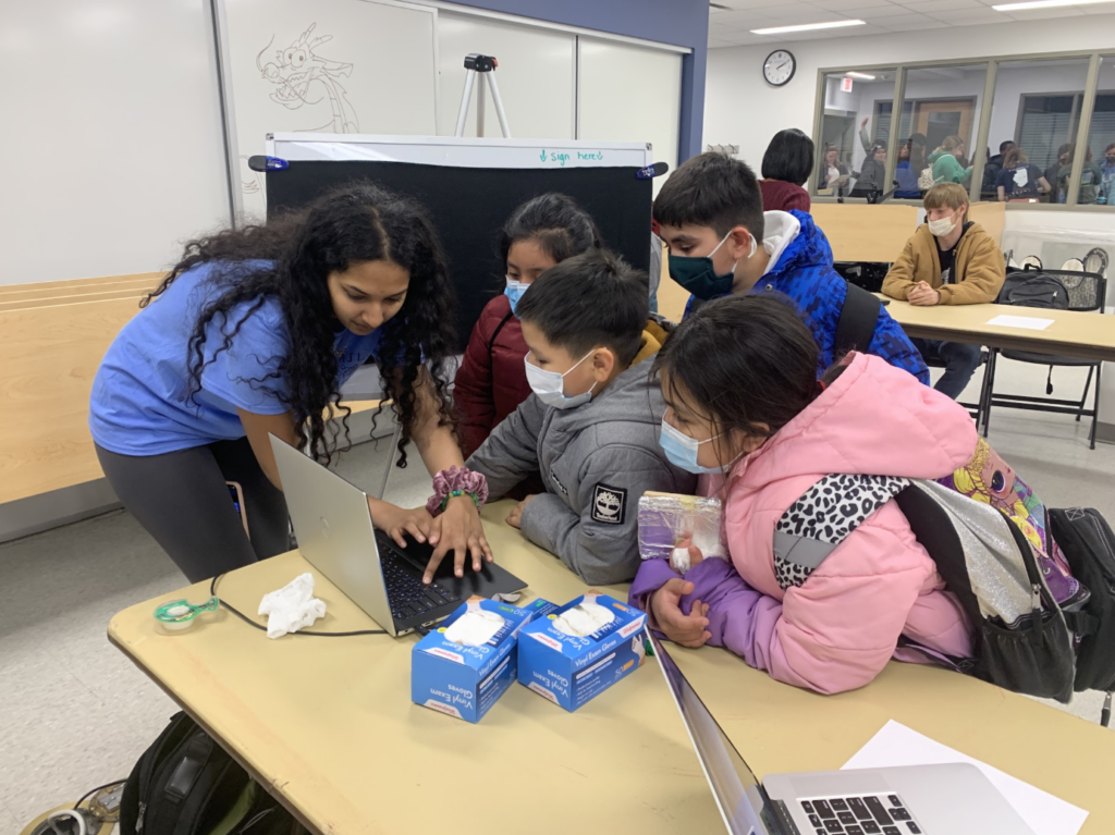 An ASL Aspire volunteer assisting children in a classroom